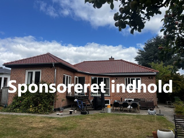 Muret hus med nyt rødt tegltag set fra haven en solskinsdag